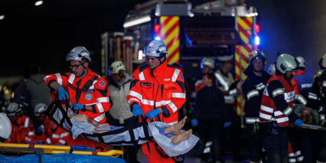 Mehrere Rettungskräfte und oder Feuerwehrmänner versorgen eine Puppe.